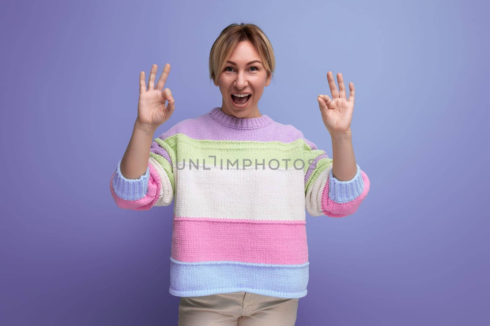 cute attentive blond young woman showing class gesture on purple background.