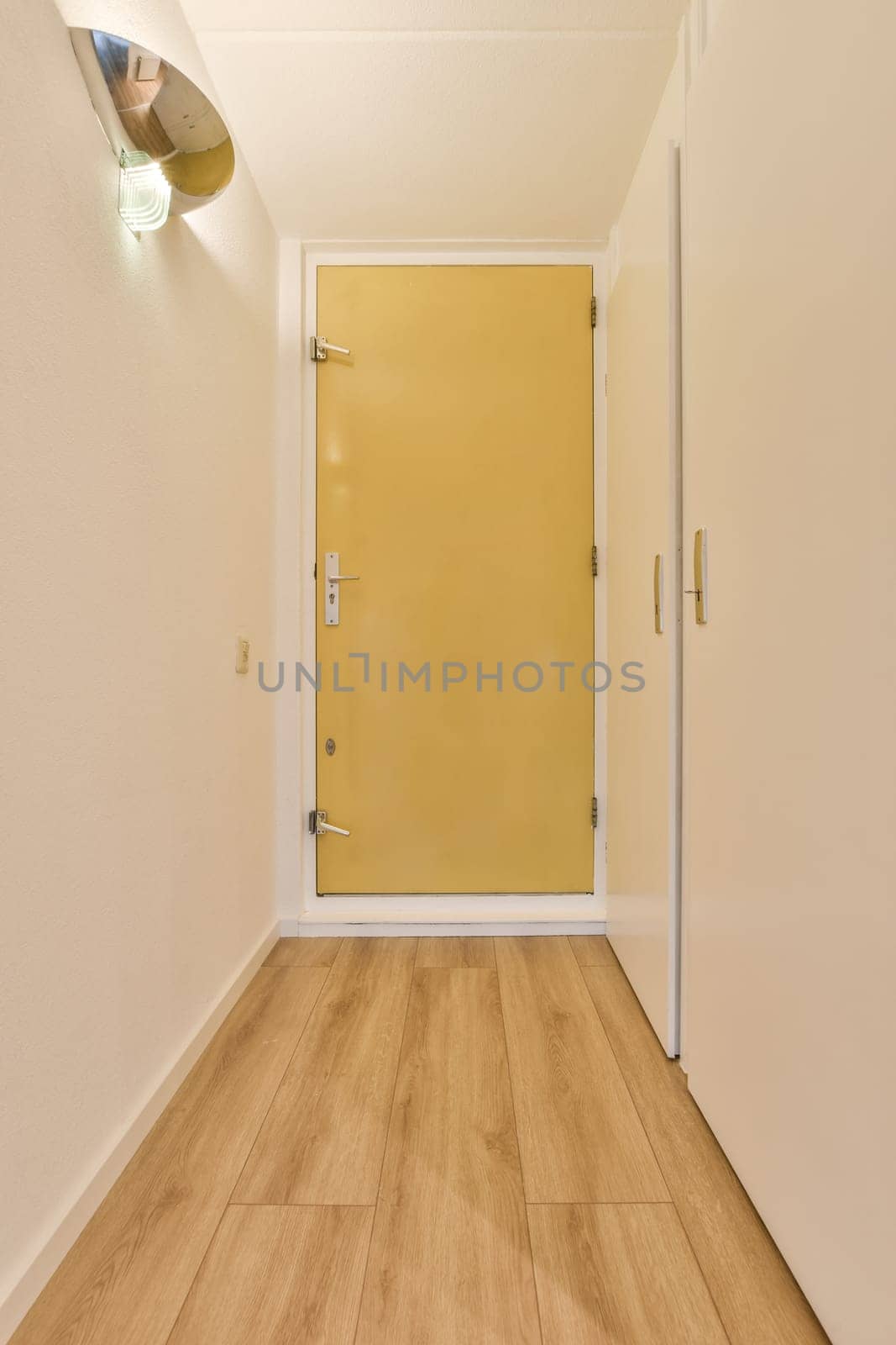 an empty room with yellow door and wooden floor in the corner, looking towards the entrance to the living room