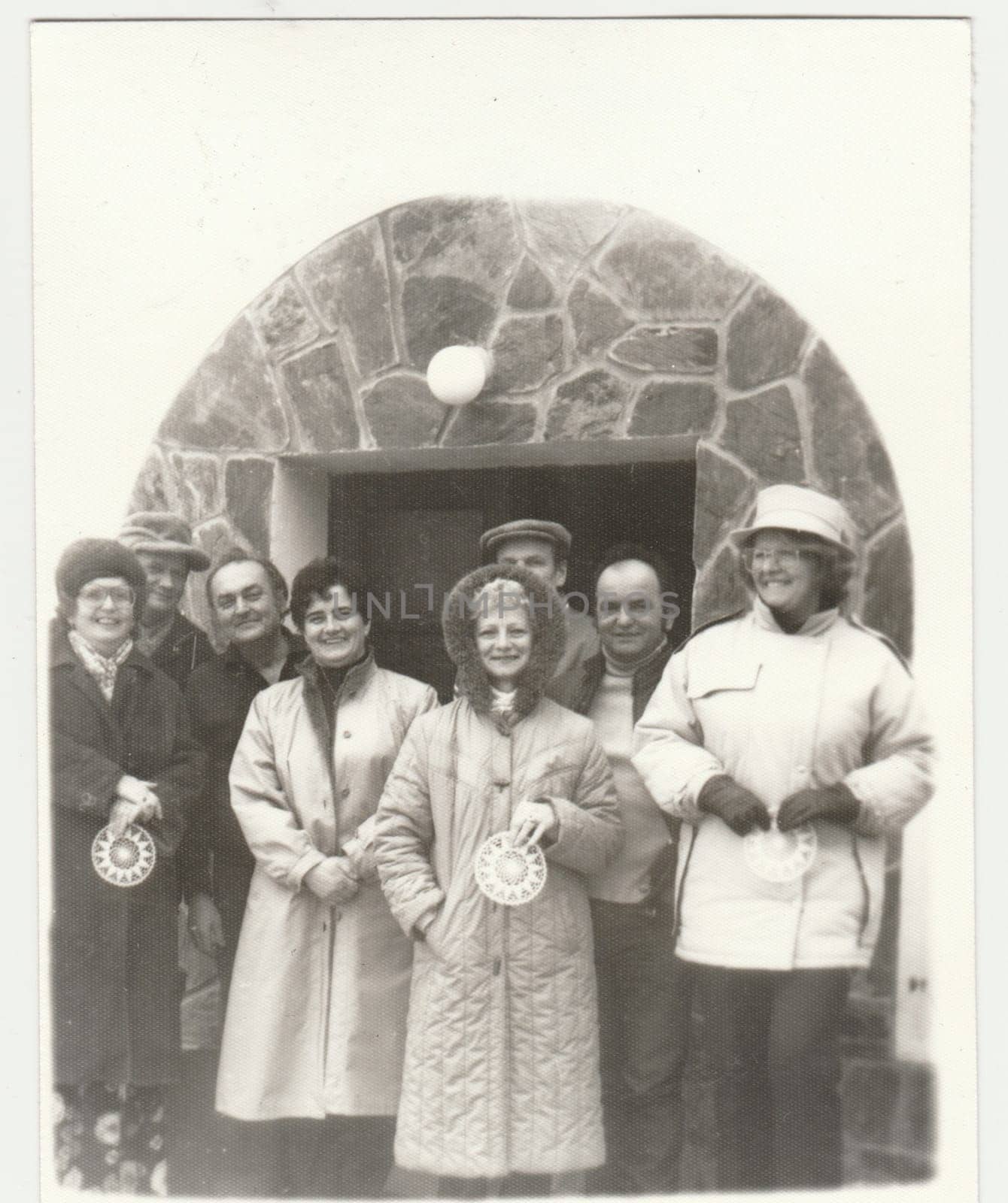 Vintage photo shows group of people poses outdoors in winter time. Retro black and white photography. Circa 1980s. by roman_nerud