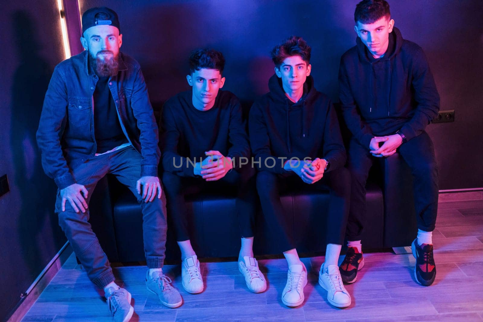 Group of people is together in the studio with futuristic neon lighting.