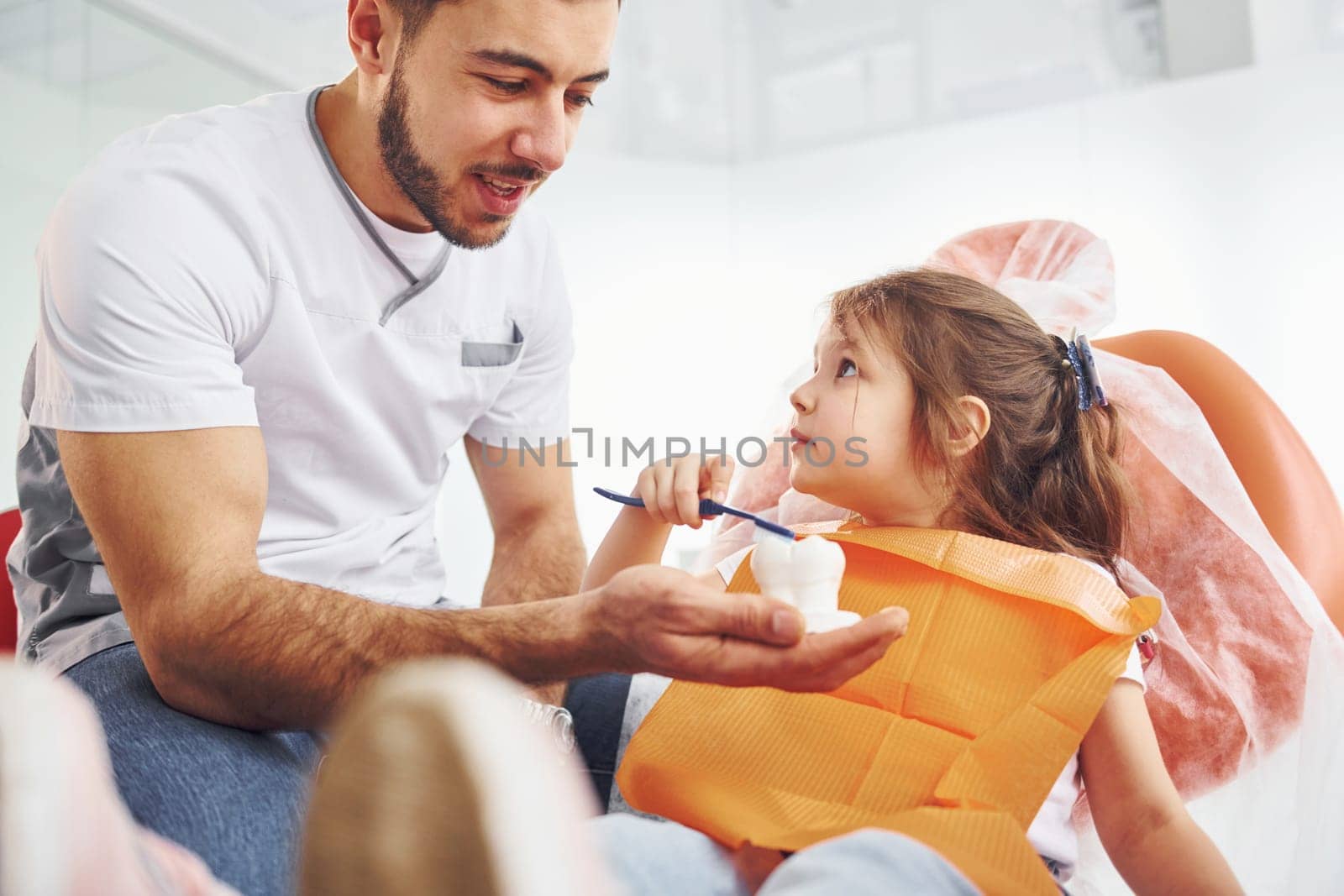 Sits on the chair. Little girl visiting dentist in clinic. Conception of stomatology.