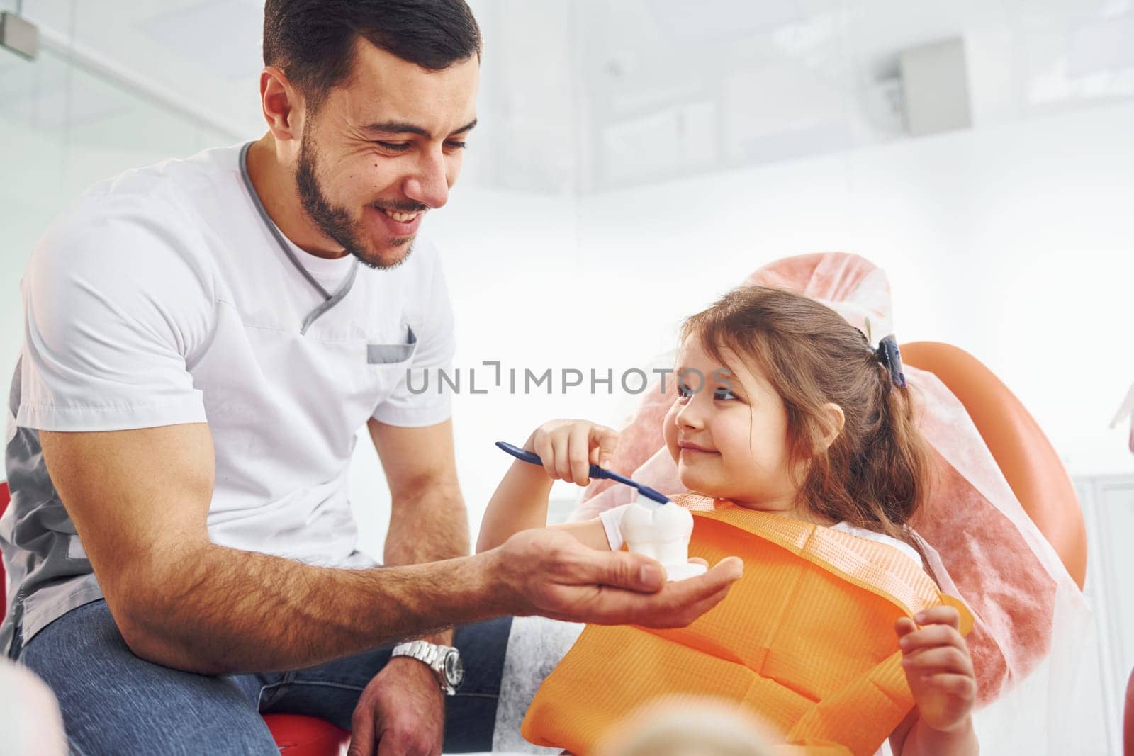 Sits on the chair. Little girl visiting dentist in clinic. Conception of stomatology.