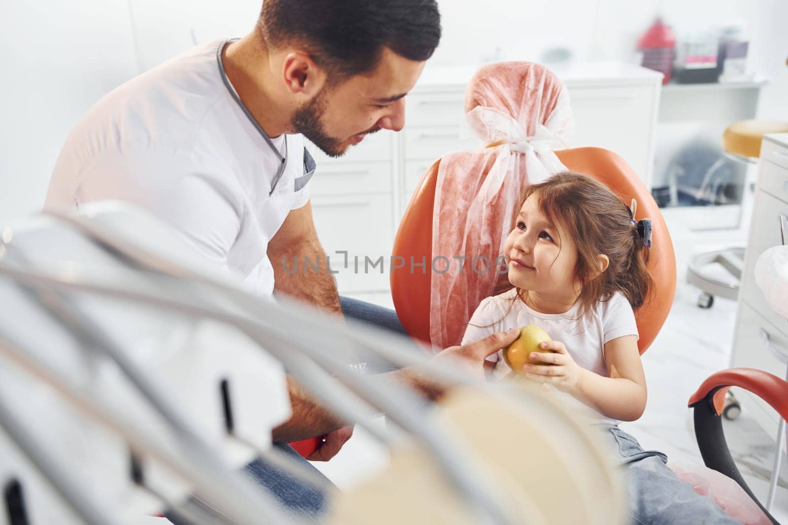 Sits on the chair. Little girl visiting dentist in clinic. Conception of stomatology.