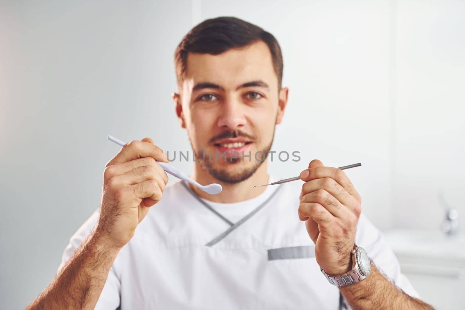 Portrait of professional dentist with equipment that standing indoors.