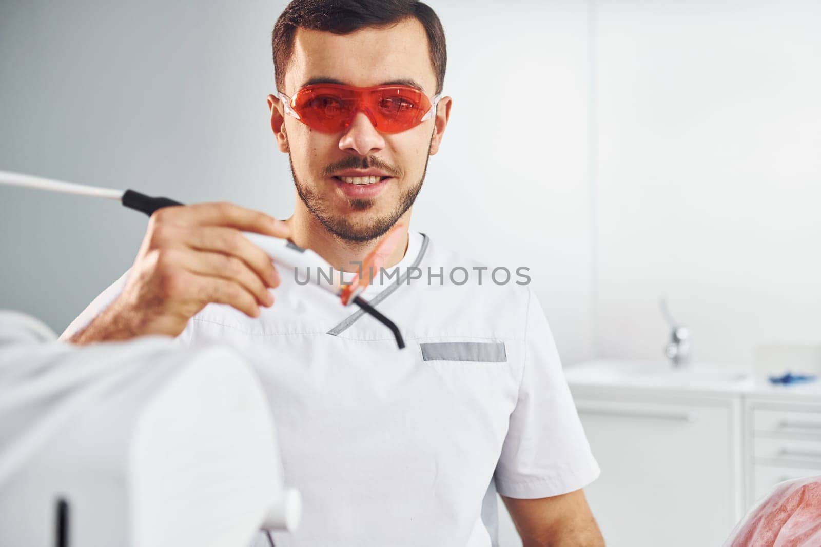 Portrait of professional dentist with equipment that standing indoors.