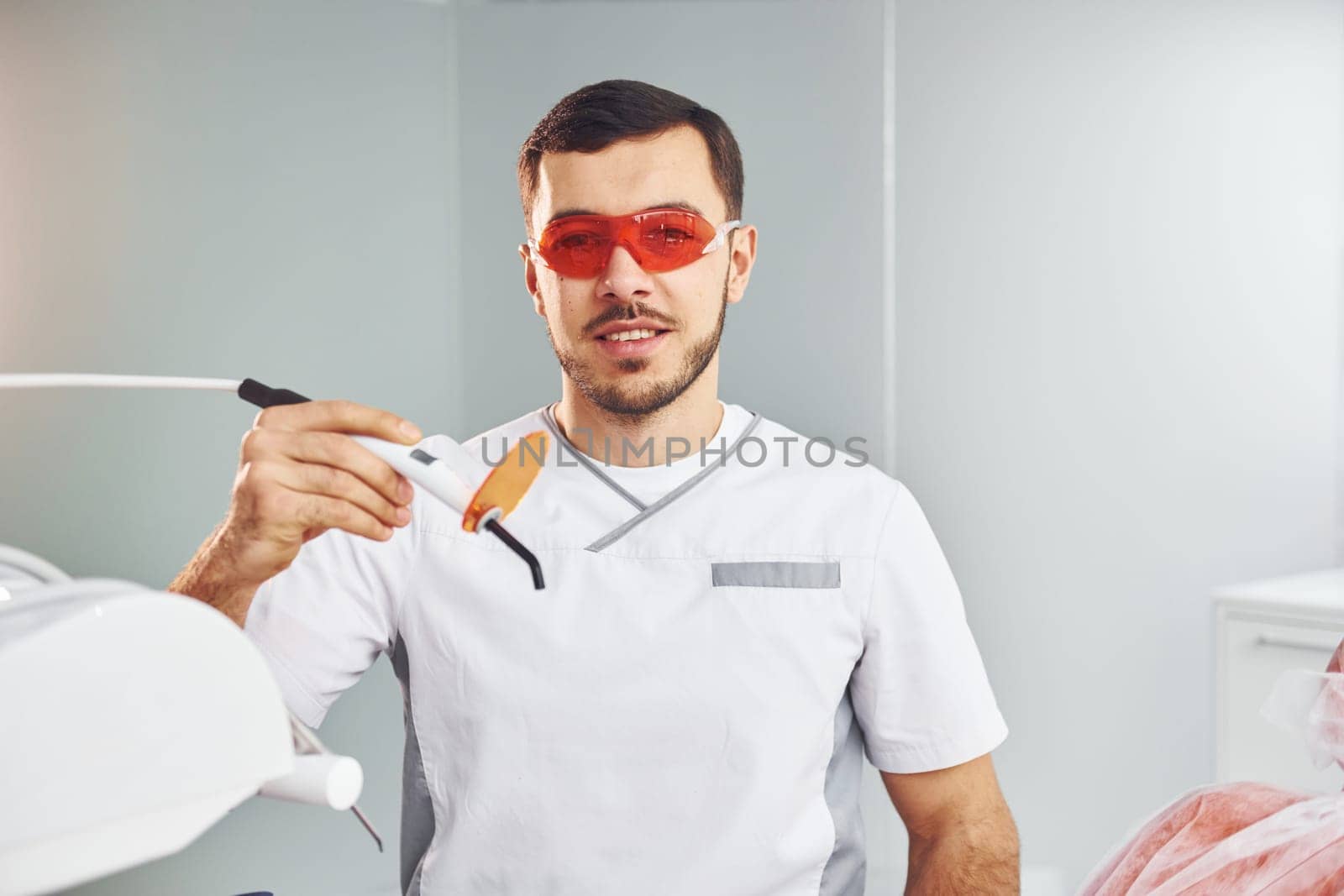 Portrait of professional dentist with equipment that standing indoors.