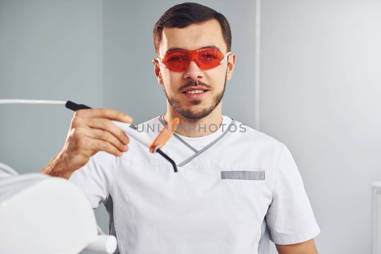 Portrait of professional dentist with equipment that standing indoors by Standret