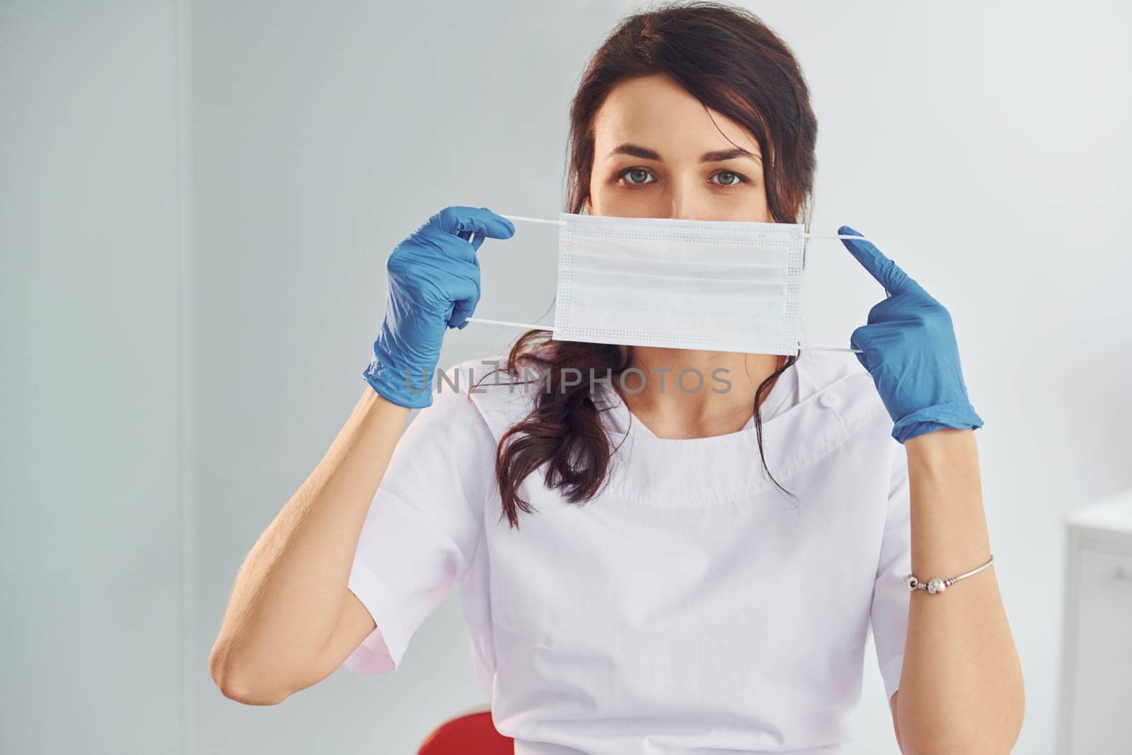 Medical mask. Portrait of professional female dentist with equipment that standing indoors by Standret