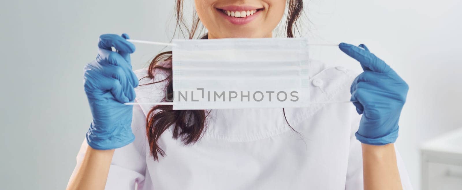 Medical mask. Portrait of professional female dentist with equipment that standing indoors.