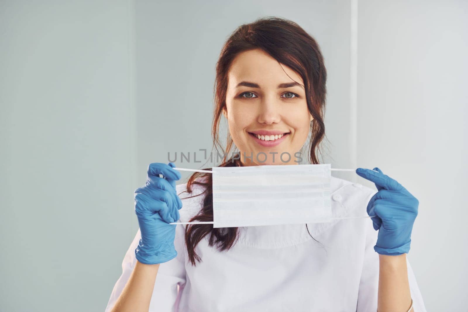 Medical mask. Portrait of professional female dentist with equipment that standing indoors by Standret