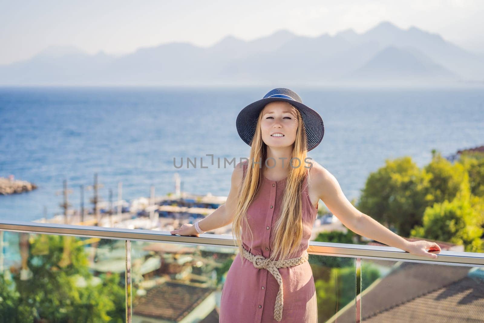 Woman tourist in Old town Kaleici in Antalya. Turkiye. Panoramic view of Antalya Old Town port, Taurus mountains and Mediterrranean Sea, Turkey.