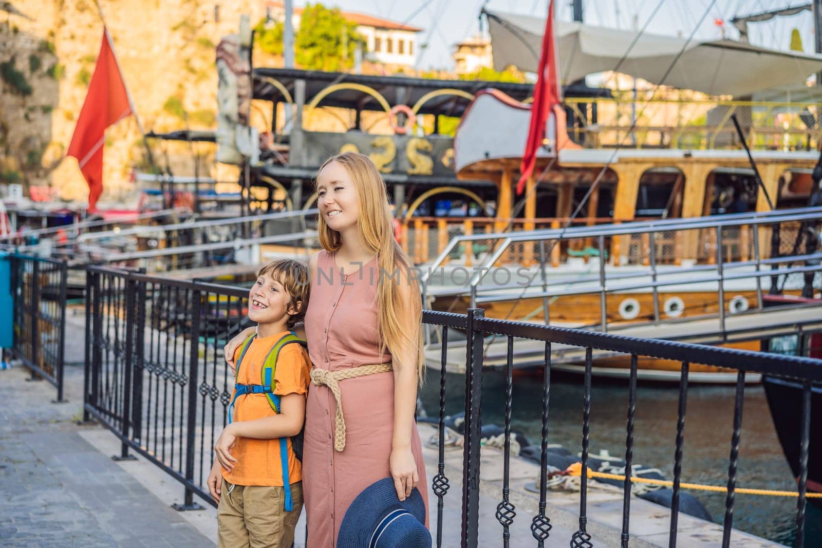 Mom and son tourists in Old town Kaleici in Antalya. Turkiye. Panoramic view of Antalya Old Town port, Taurus mountains and Mediterrranean Sea, Turkey. Traveling with kids concept.