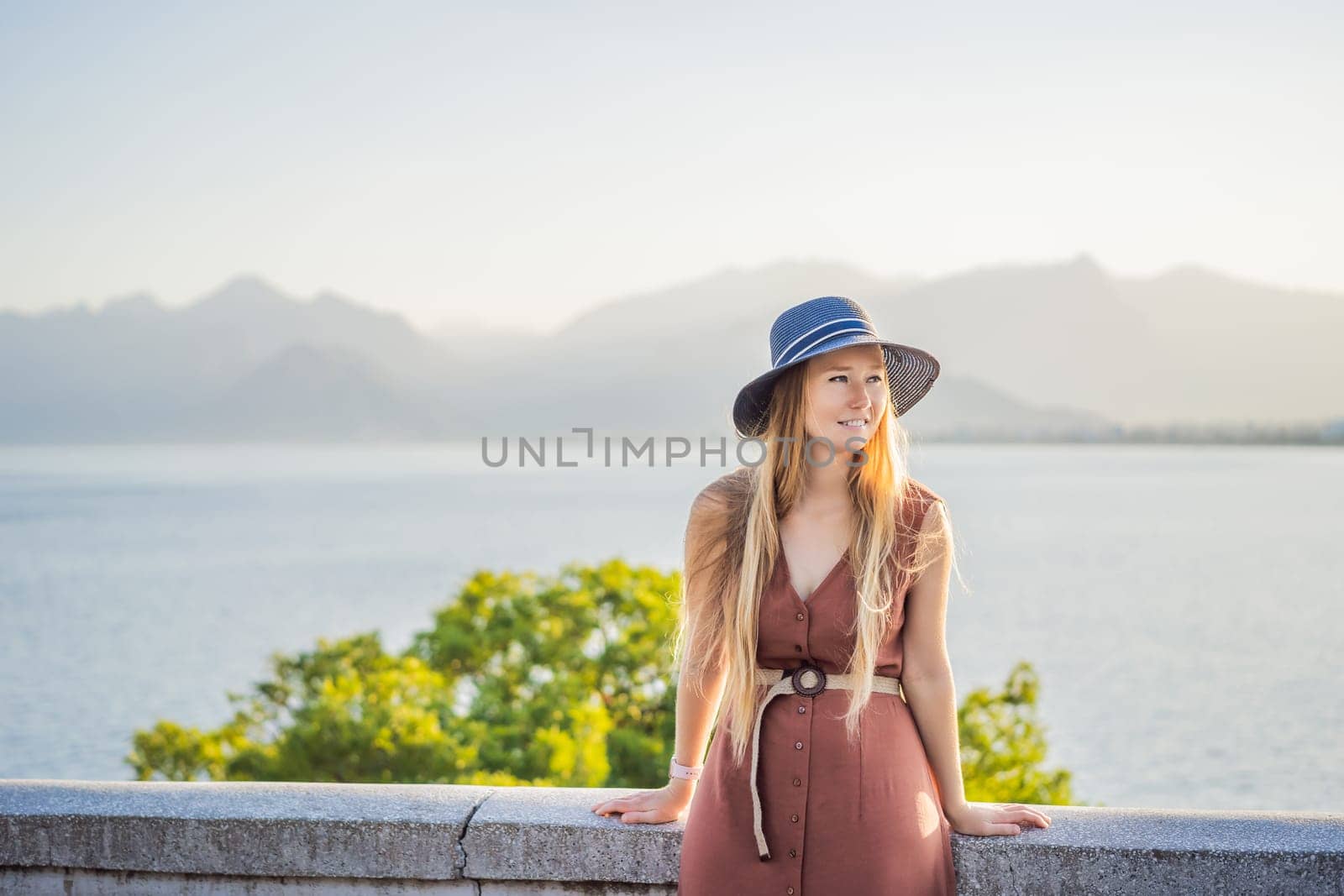 Happy woman tourist on background of Antalya sea and mountain views, sea in Turkey Antalya City. female tourist traveler discover interesting places and popular attractions and walks in the old city Kalechi of Antalya, Turkey. Turkiye.