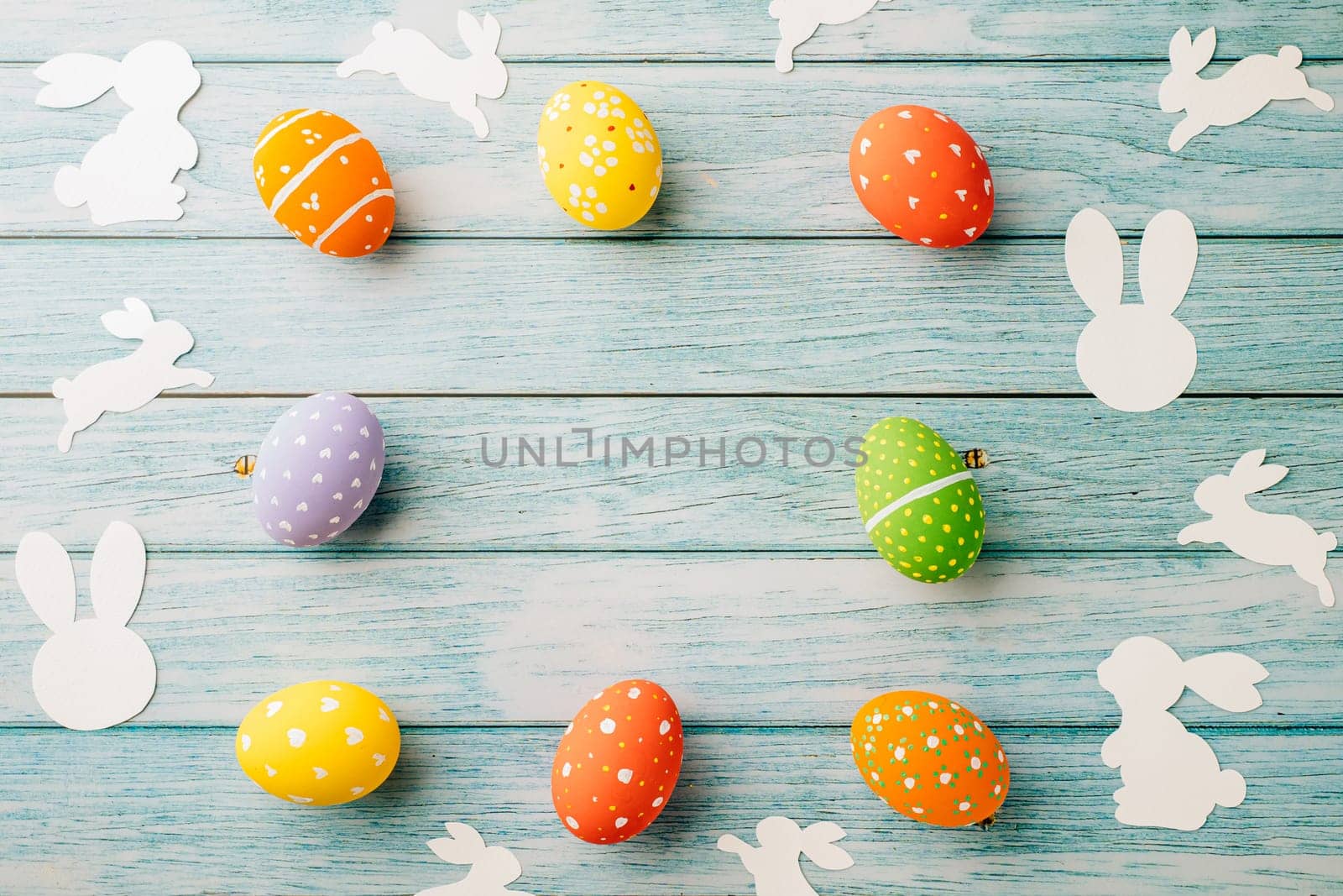 Easter Day Concept. Top view holiday banner background web design white colorful easter eggs and paper bunny rabbit on blue wood background with copy space, celebration greeting, overhead, template