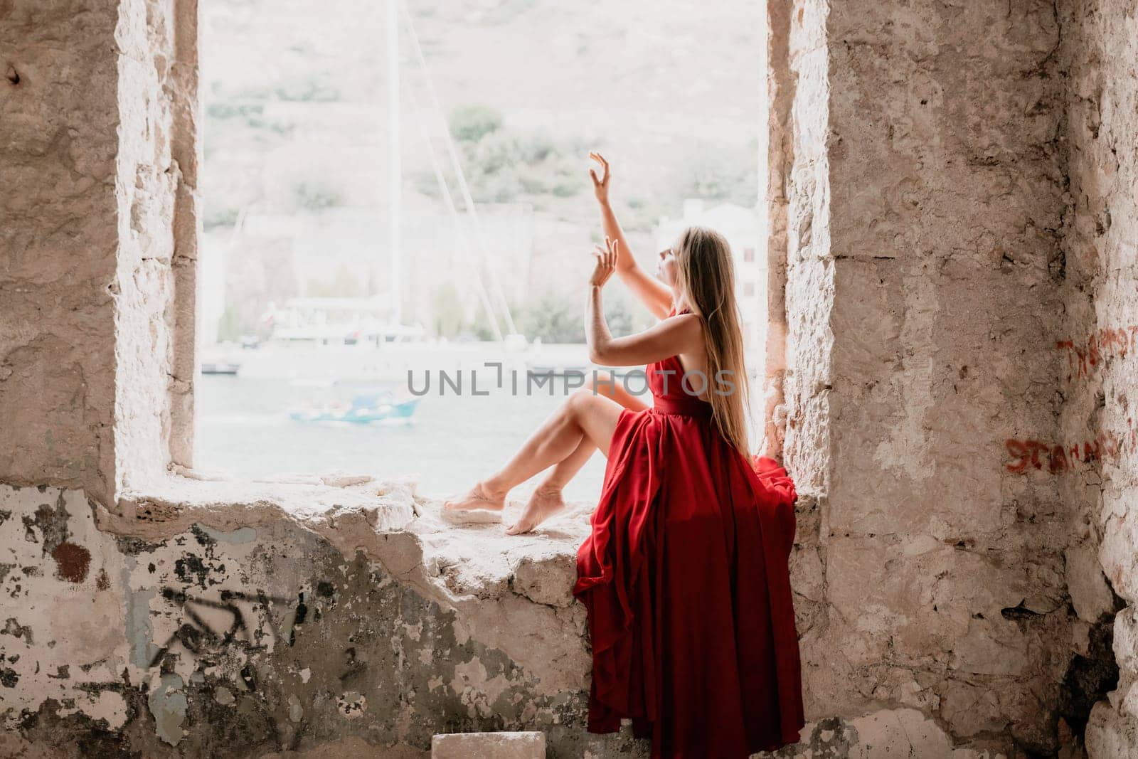 Woman travel portrait. Happy woman with long hair looking at camera and smiling. Close up portrait cute woman in a res long dress posing on backdrop of old travel city near sea by panophotograph