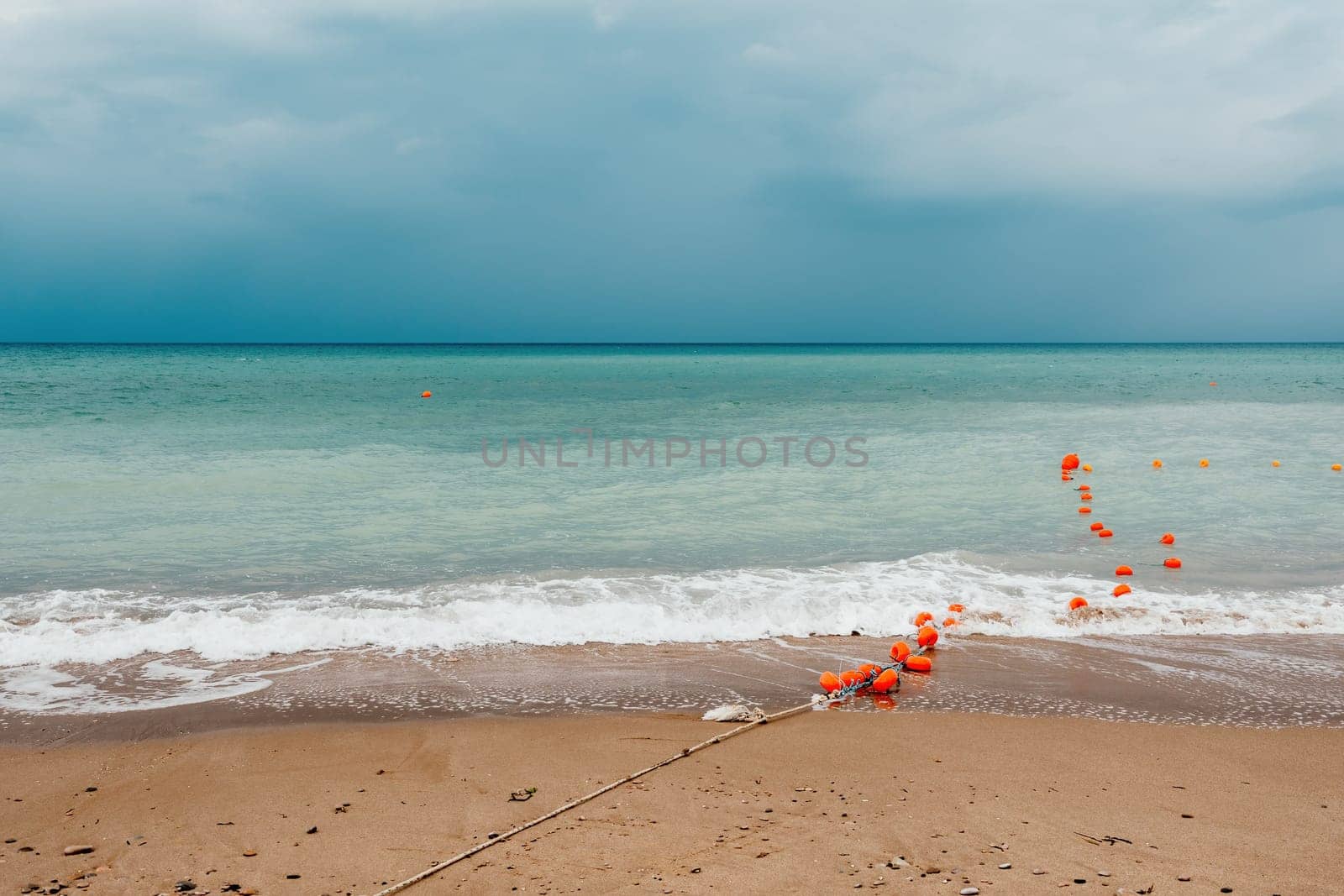 Overcast sky on rainy day with foamy waves rolling towards golden sand beach under low warm sun light. Nobody. Holiday recreation concept. Abstract nautical summer ocean sunset nature. by panophotograph