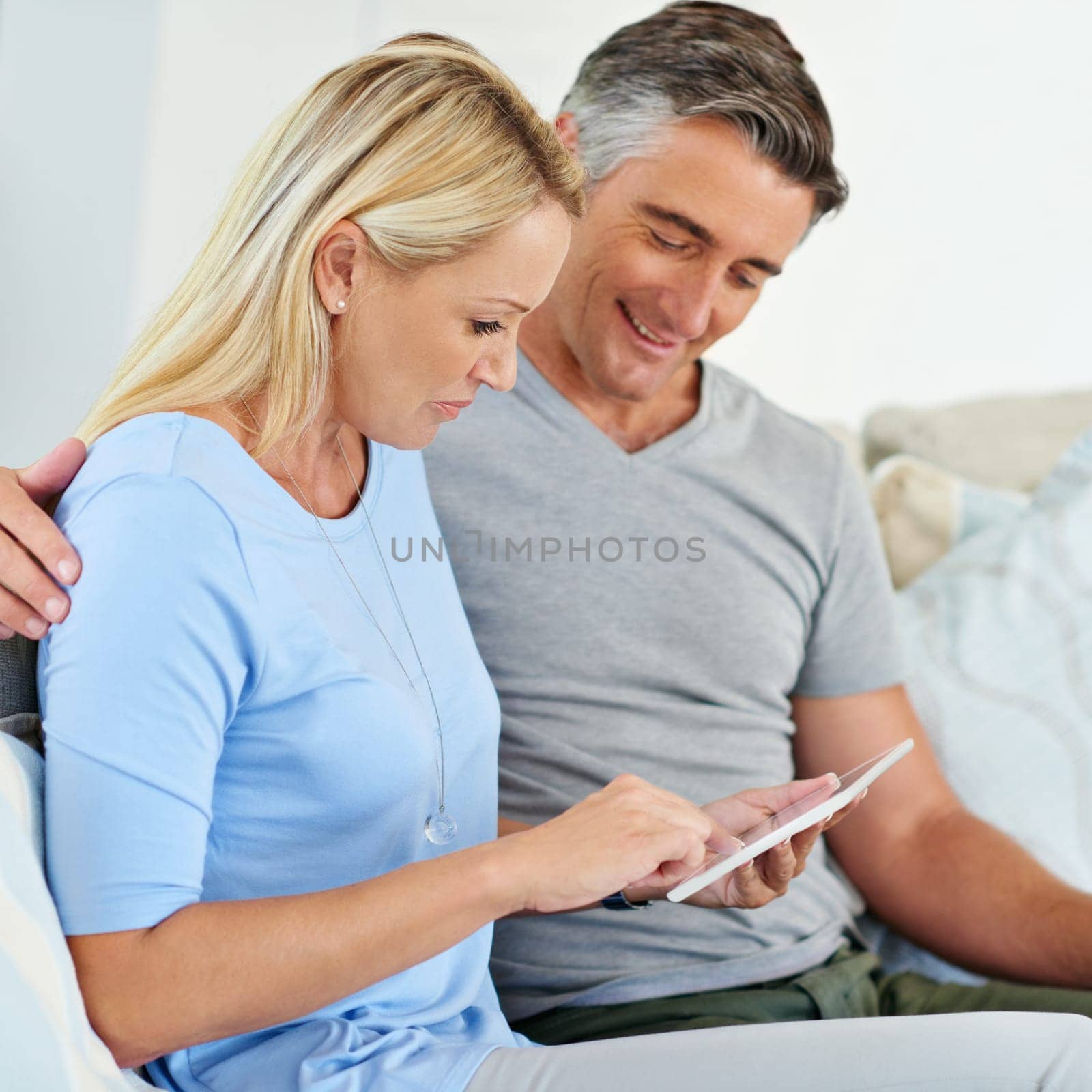 Living their digital lifestyle. a mature couple sitting at home using a digital tablet. by YuriArcurs