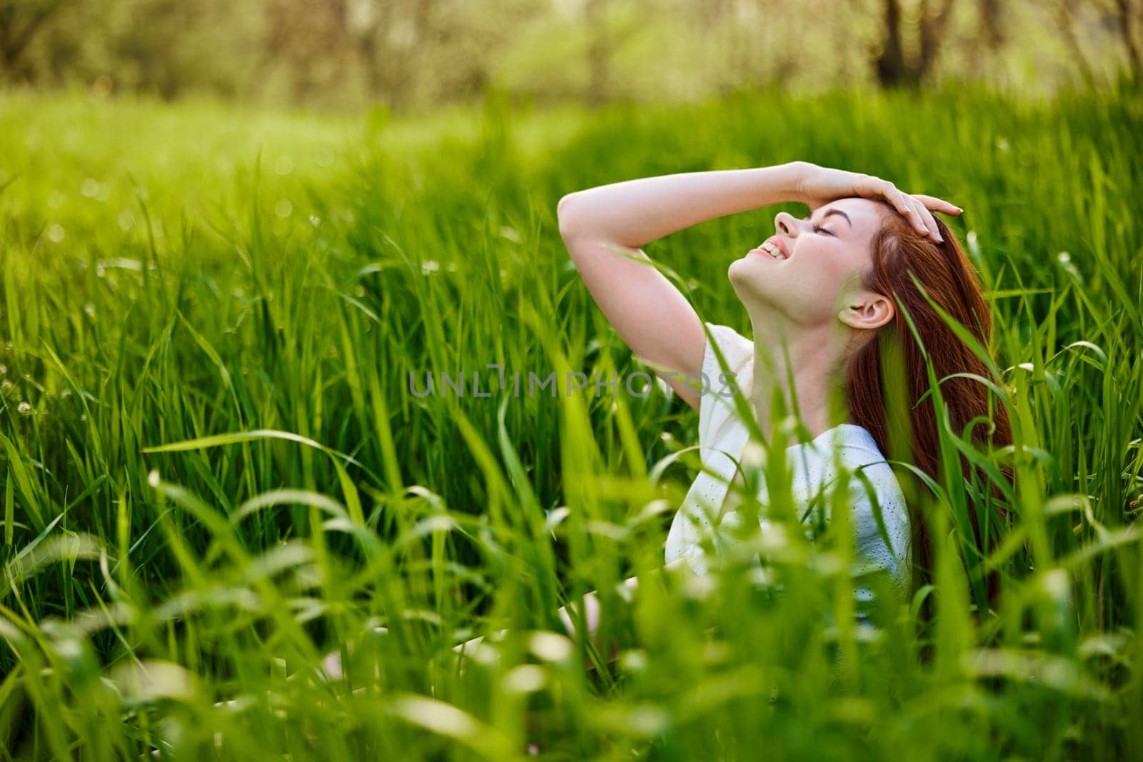 a red-haired woman stands in the tall grass, raising her oxen up and laughing widely with her teeth. High quality photo
