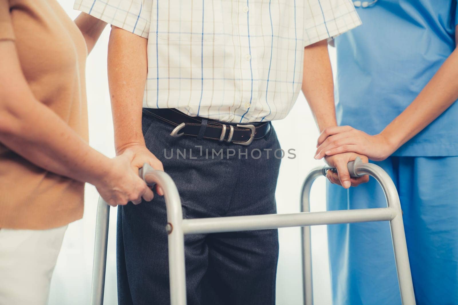 Contented senior man was helped on folding walking by his wife and caregiver. Recuperation for elderly, seniors care, nursing home.