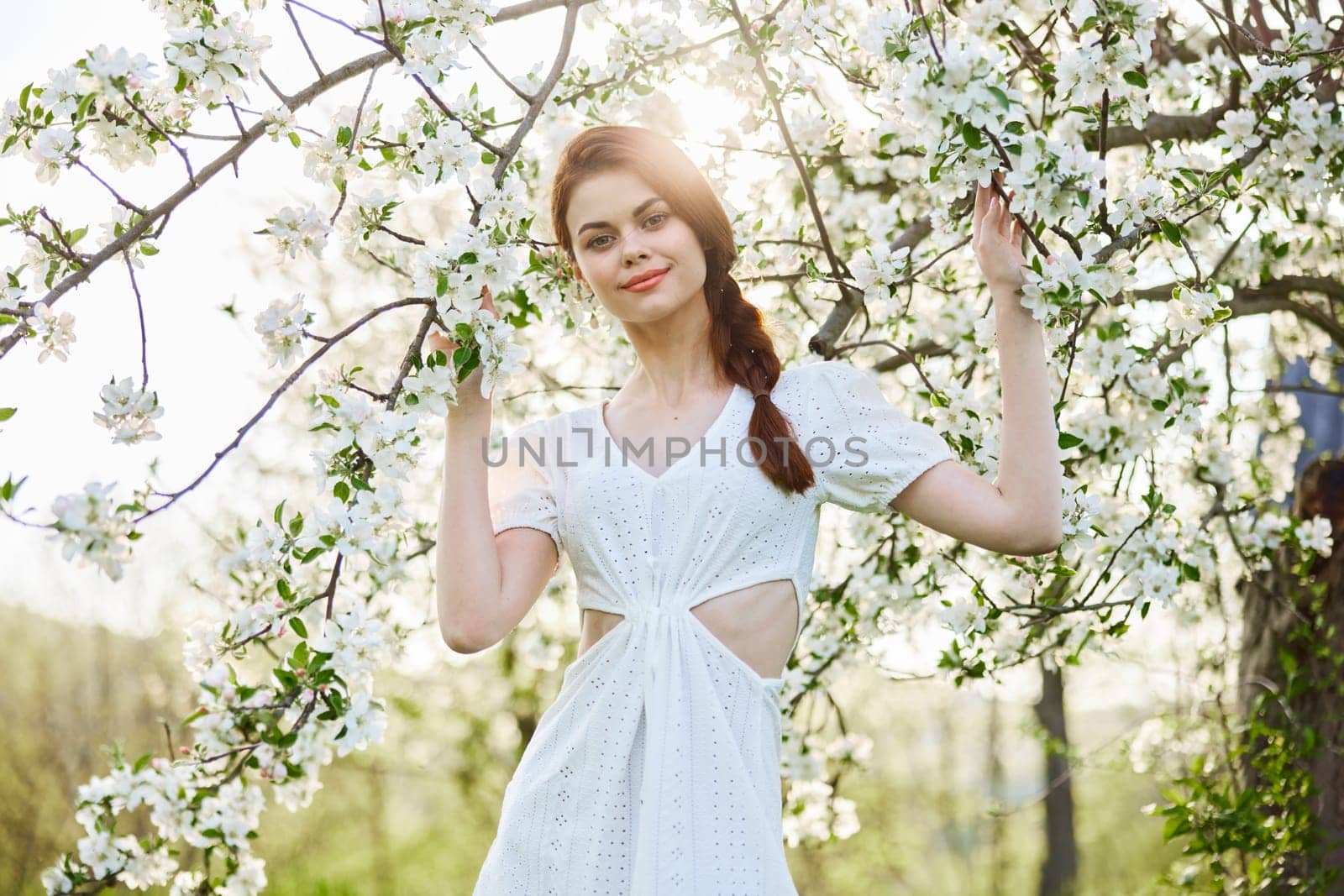portrait of a happy, laughing red-haired woman next to a flowering tree in the garden by Vichizh