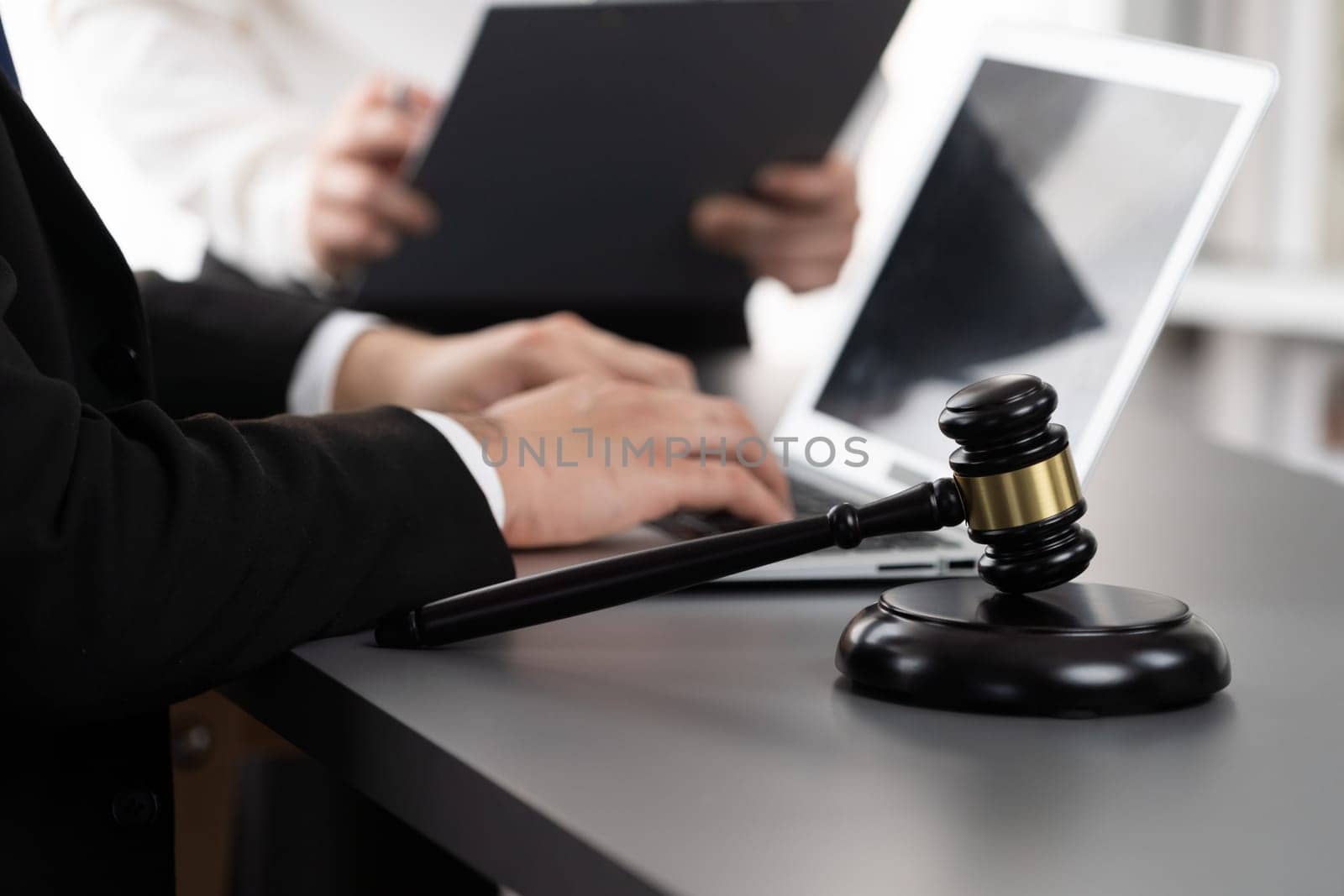 Focus gavel hammer for righteous and equality judgment with blur background of lawyer colleagues or legal team working with laptop, drafting legal documents for litigation at law firm. Equilibrium