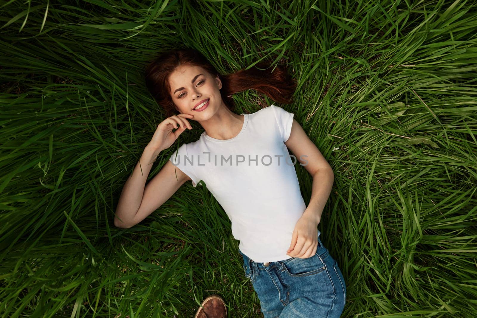 A woman in a white t-shirt lies on the grass resting fresh air by Vichizh