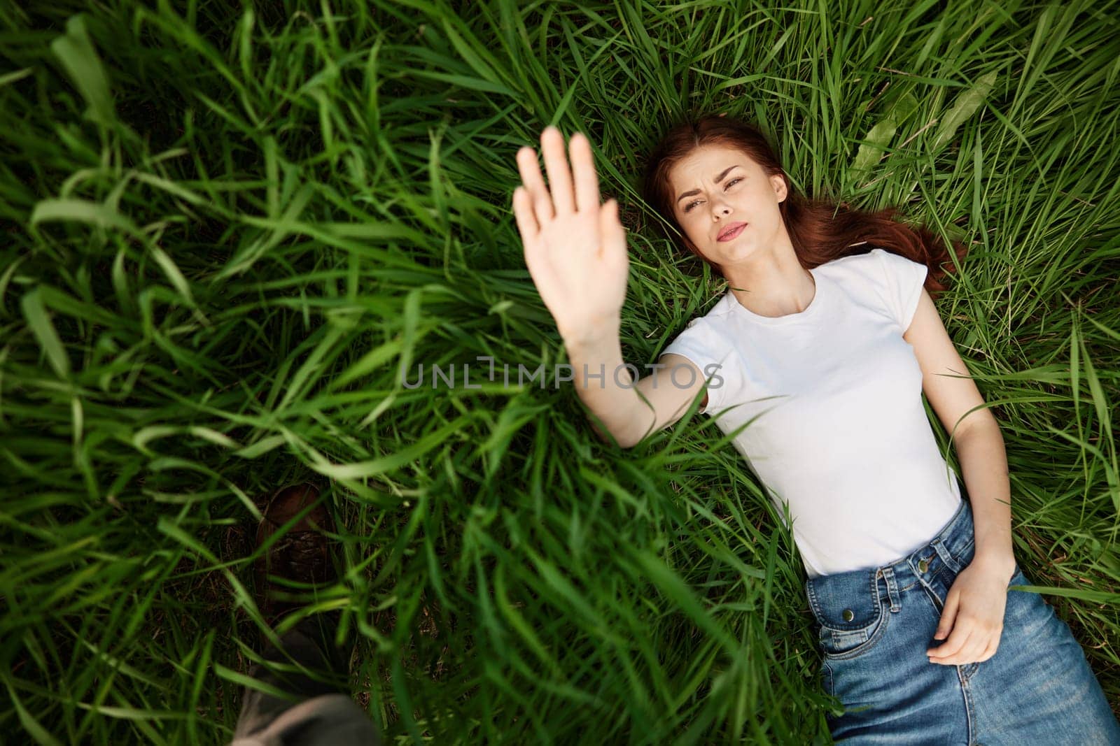 happy woman lies in high grass lit by the sun stretching her hands to the camera. High quality photo
