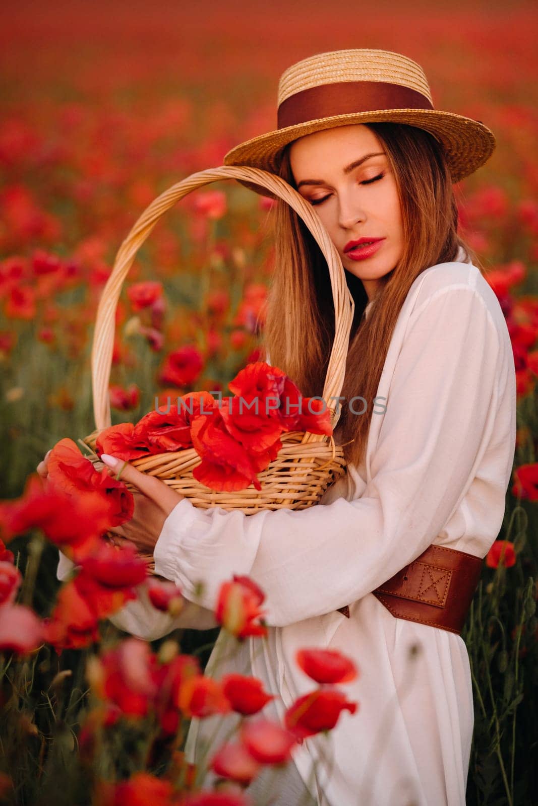 a girl in a white dress, a hat and with a basket in a field with poppies.