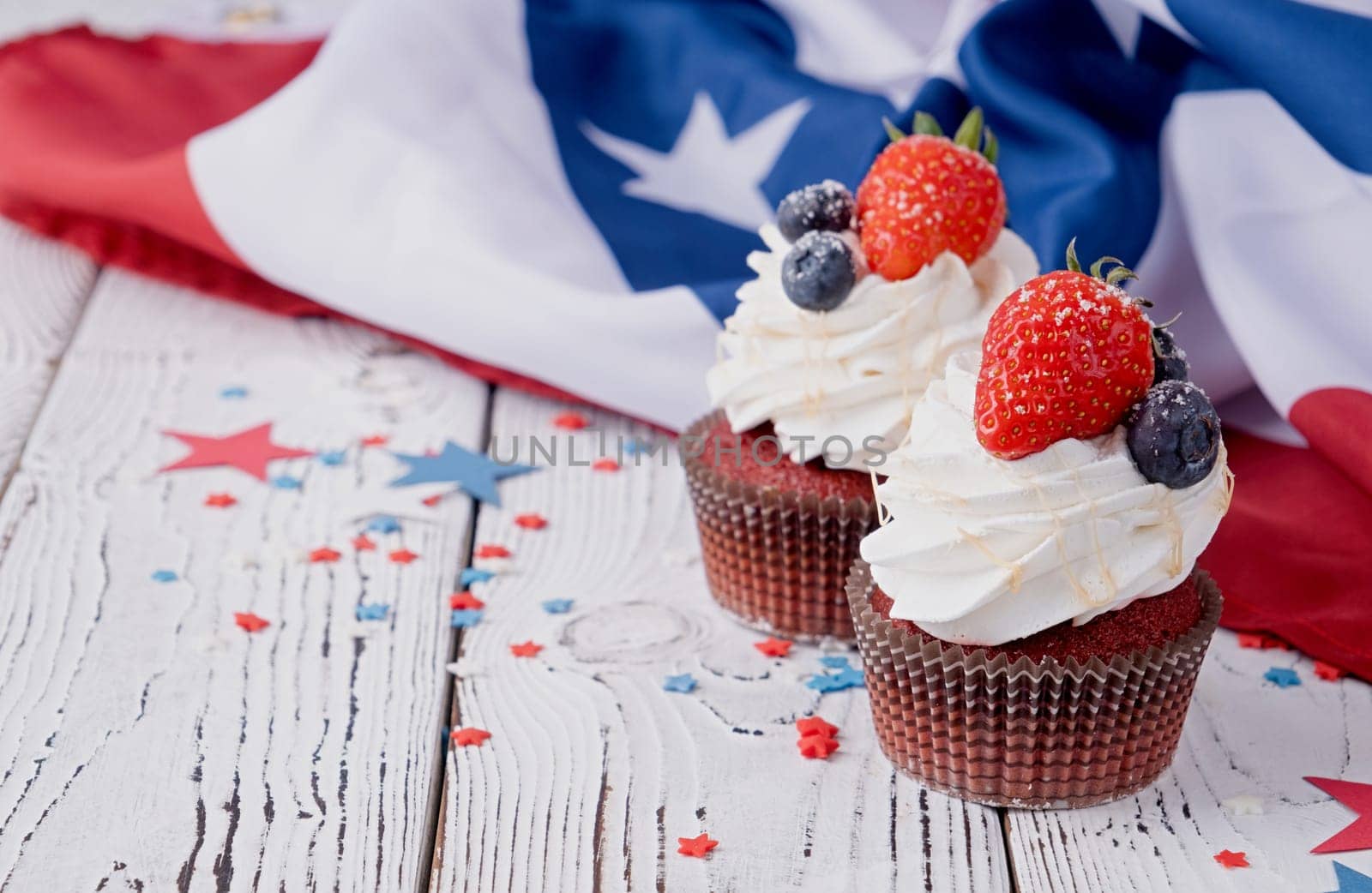 Fourth of july celebration.Sweet cupcakes with blueberries and strawberry , flag background