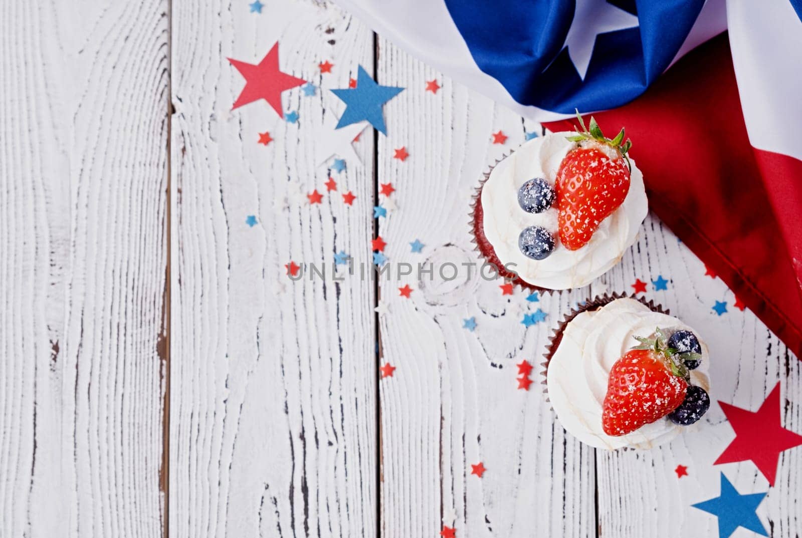 Fourth of july celebration.Sweet cupcakes with blueberries and strawberry , flag background