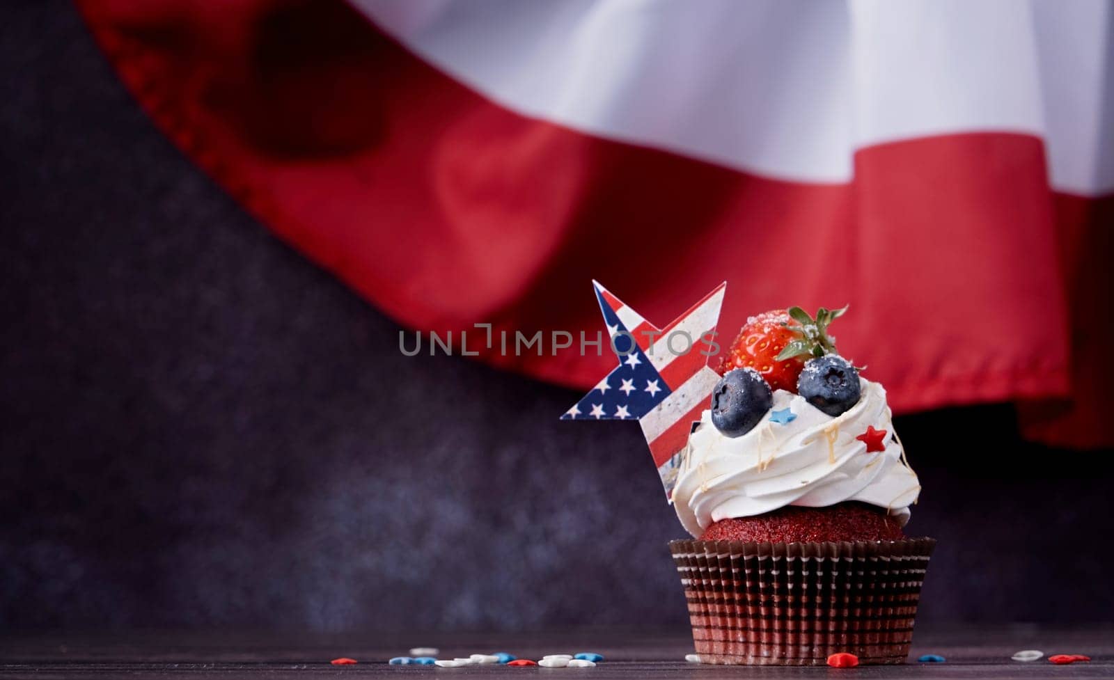 Fourth of july celebration. Sweet cupcakes with blueberries and strawberry over USA flag background