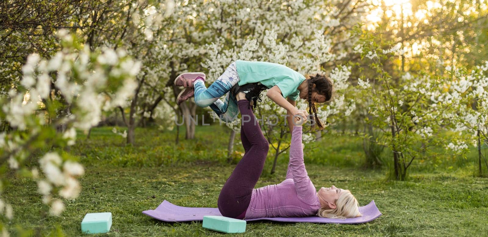 two young women and a little girl in their garden doing yoga.