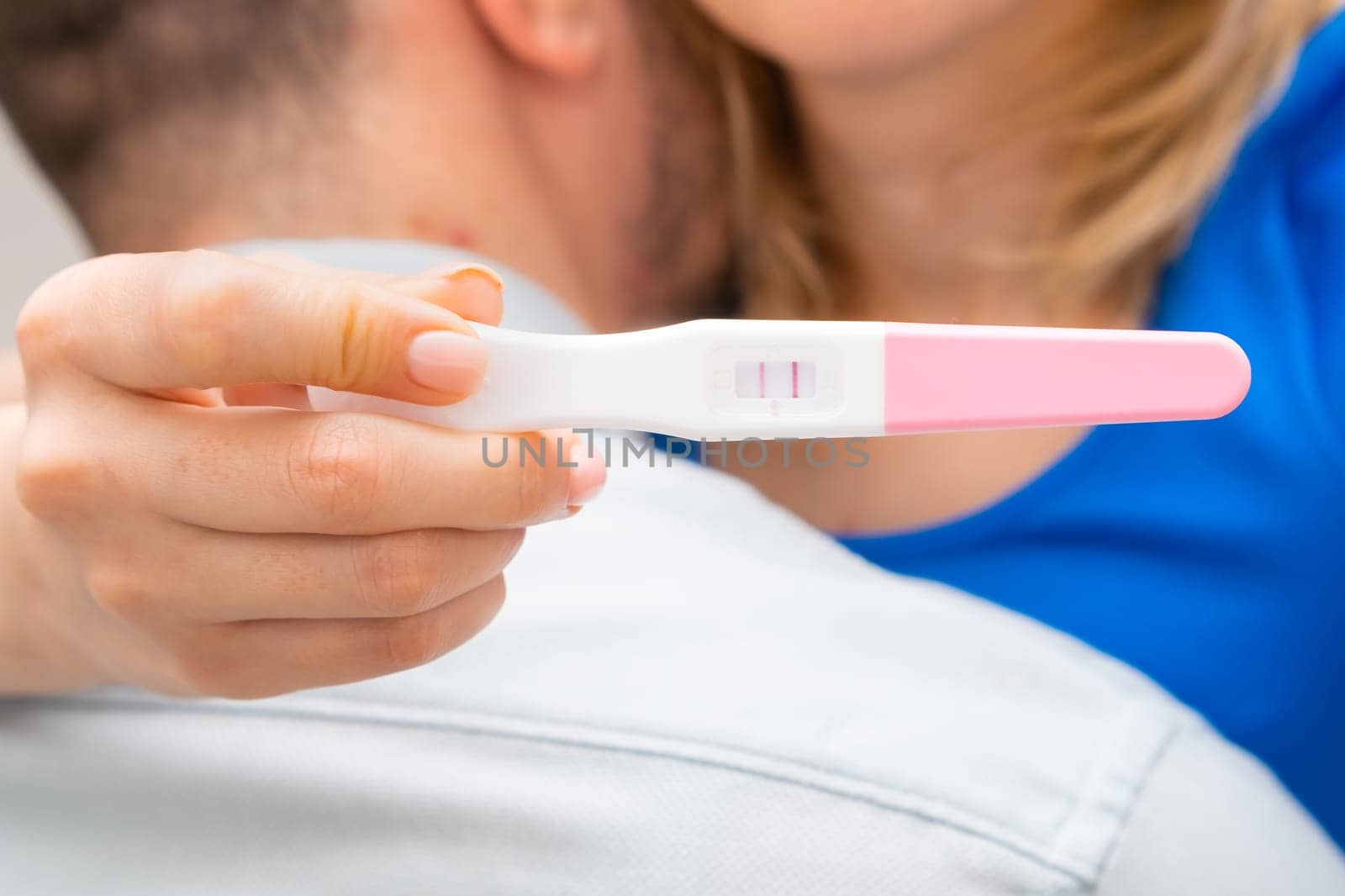 Woman hugging man and holding positive pregnancy test. Expect a baby concept.