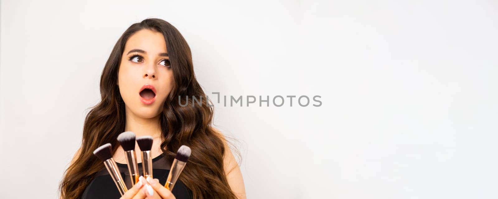 Banner with attractive excited woman holding a set of makeup brushes for professional use by vladimka