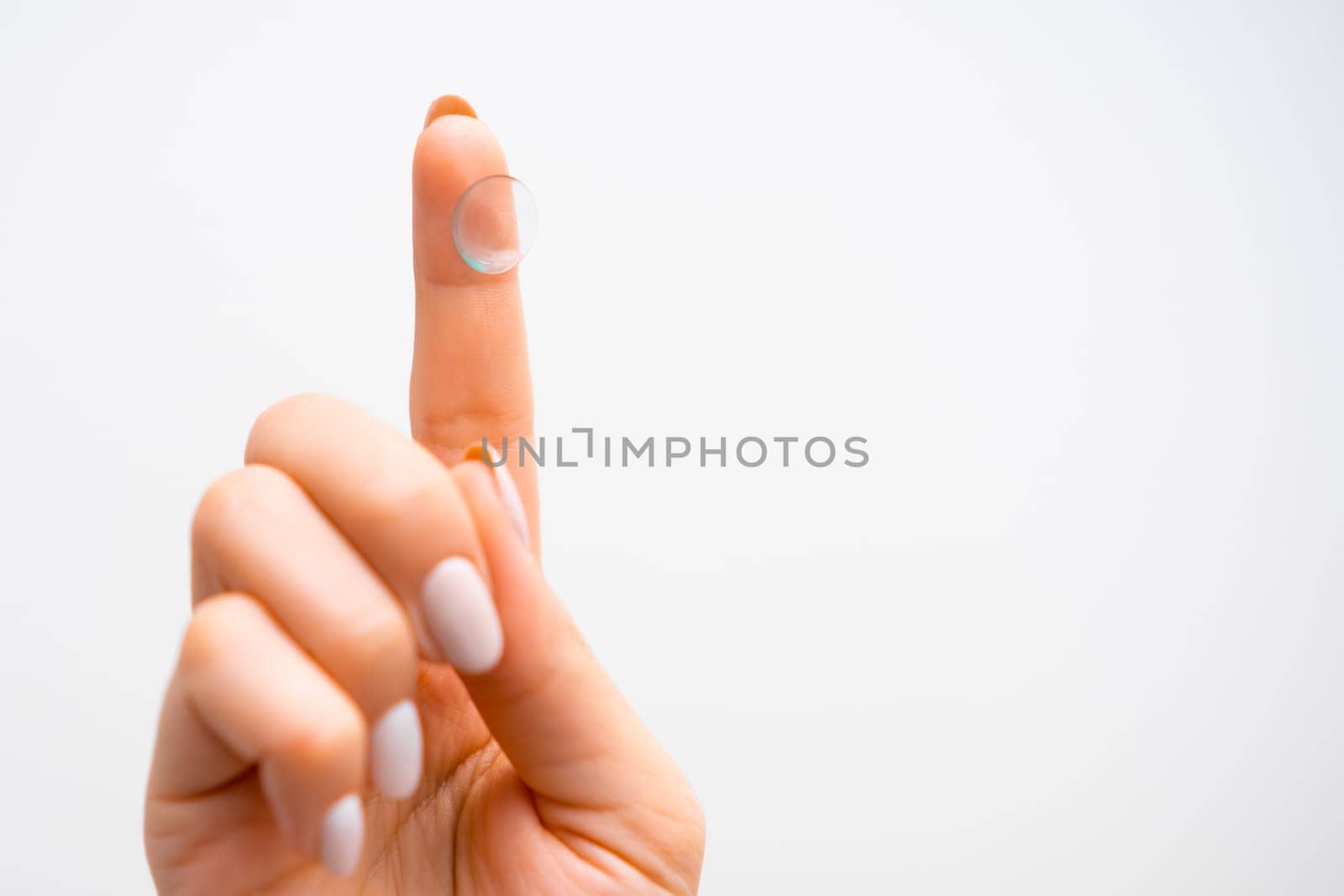 Contact lenses on the tip of womans finger on the white background with copy space. Improvement in vision or changes in eye color.