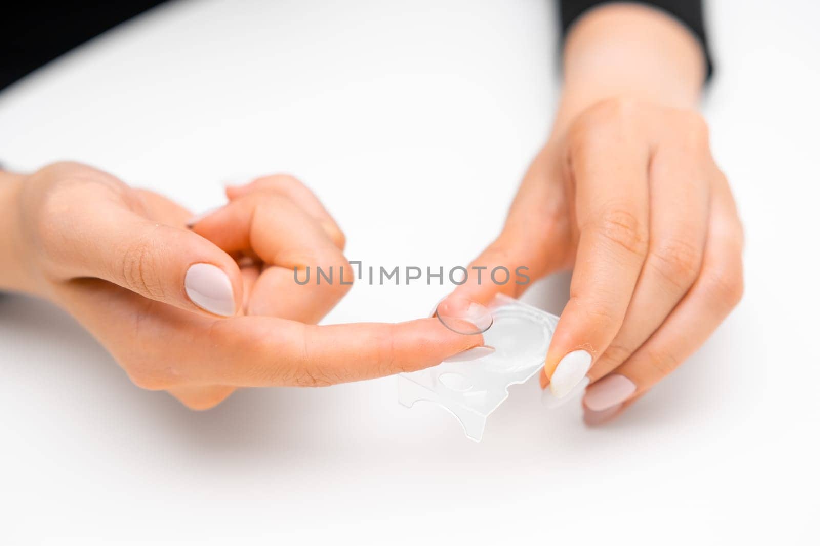 Woman takes disposable contact lenses from the blister. Eye care concept.