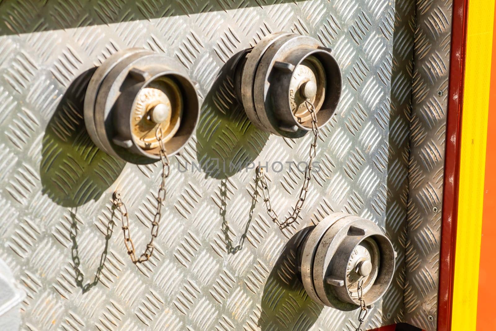 Closed with corks hose plugs on grey metal side of contemporary fire truck standing at station on sunny day extreme close view