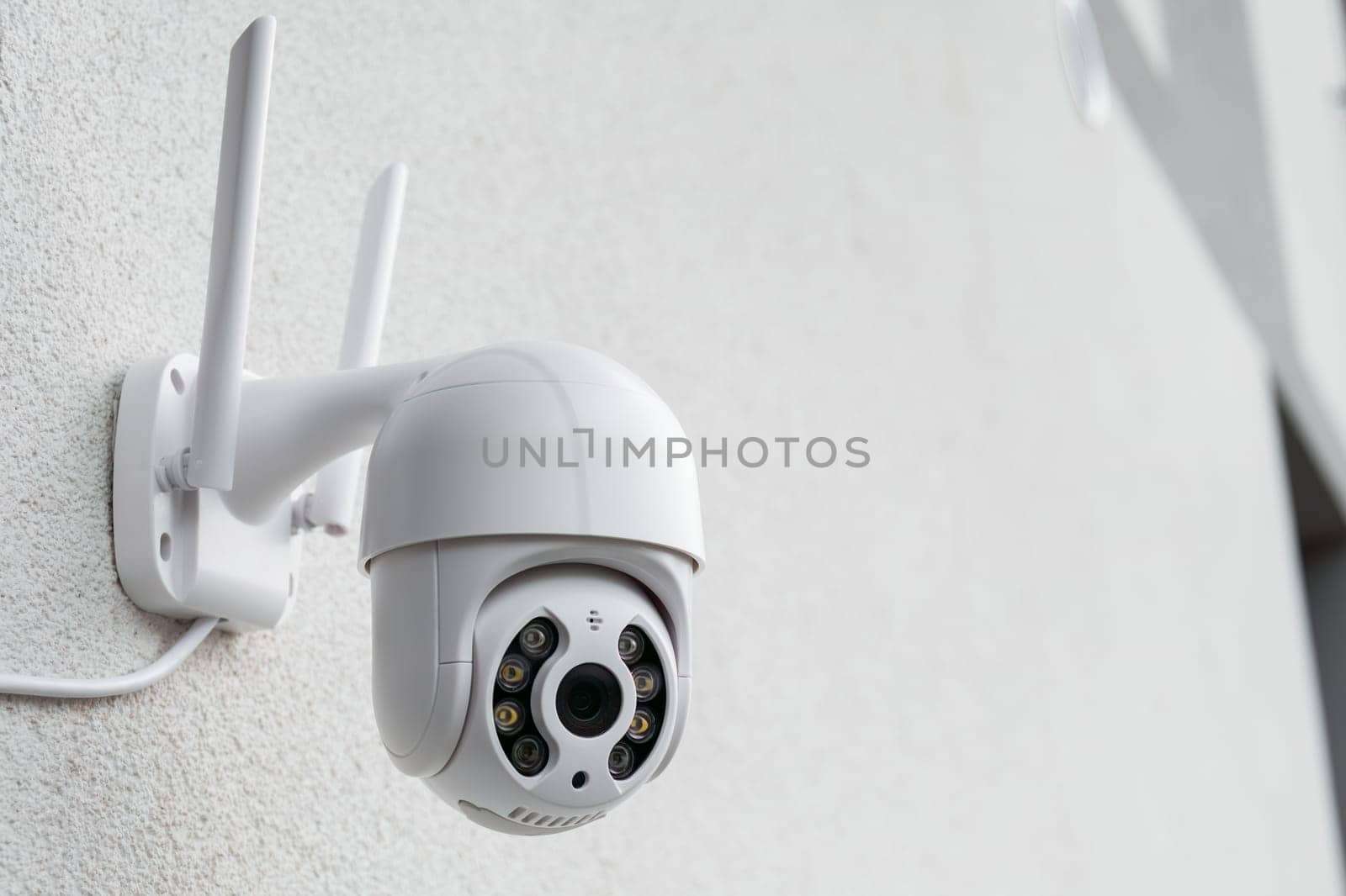 Round CCTV camera with antennas shoots video on the white wall. Digital equipment to record and broadcast real time video closeup