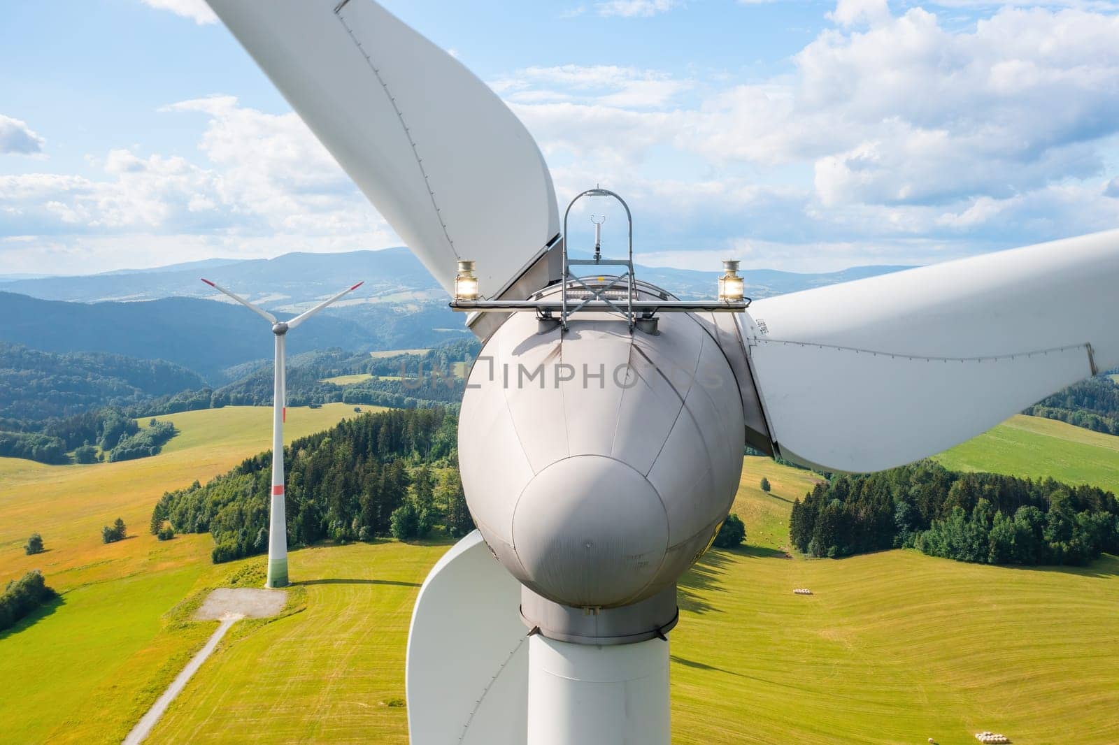 Close up a propeller of the windmill in the yellow field with mountains in the background