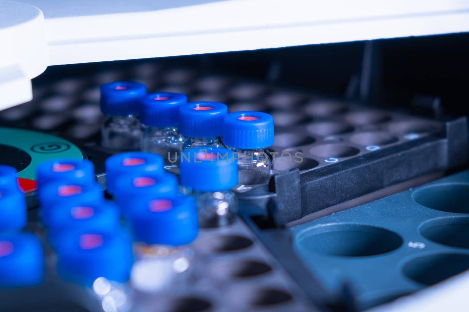 Close up vials with blue caps in the rack of auto sample for LC MS analysis. Research experiment of vaccine. Clinical analysis to detect diseases.