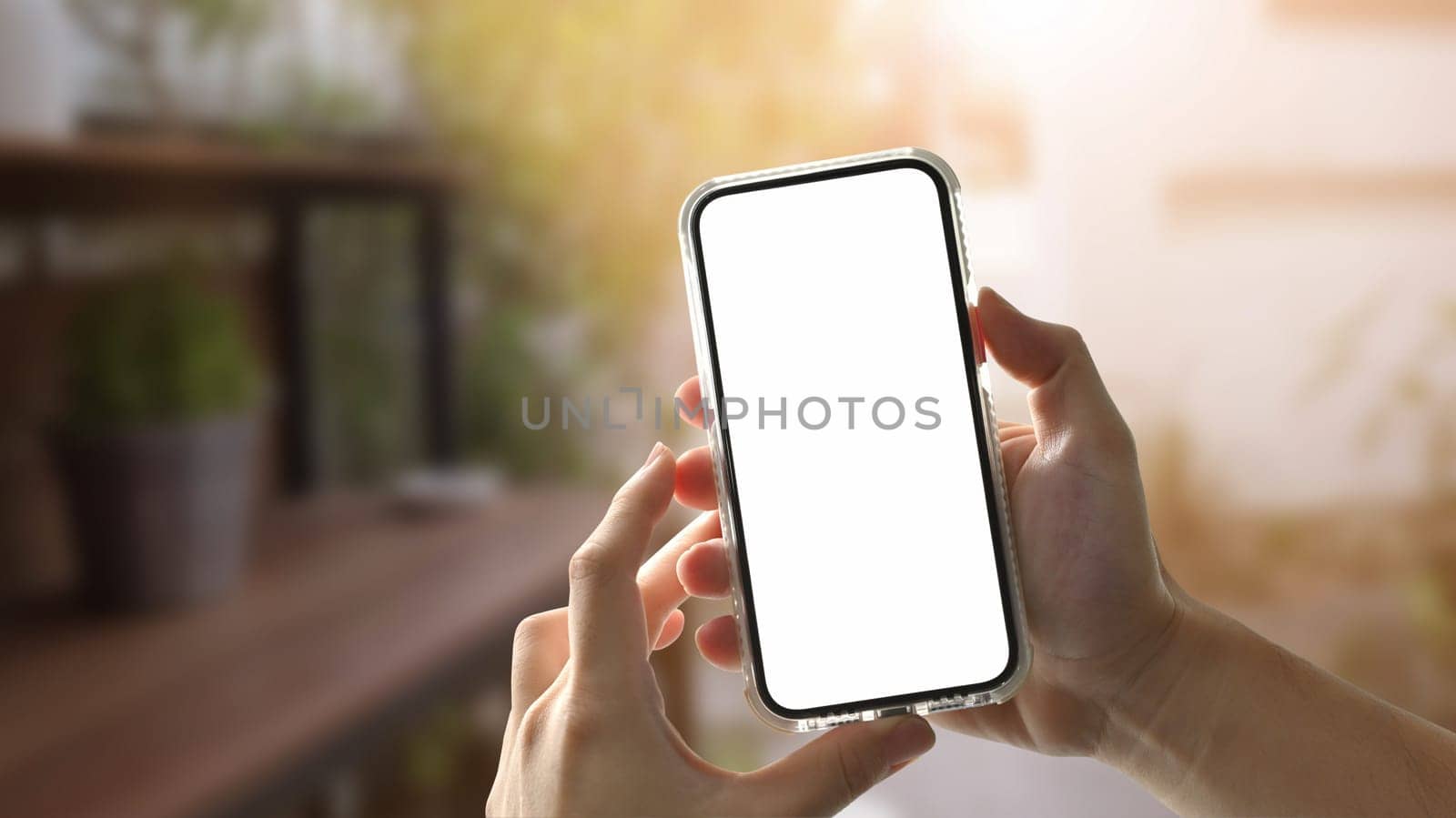 Hand holding mobile at outdoor with sunrise. Copy space screen for your text message or promotional content by prathanchorruangsak