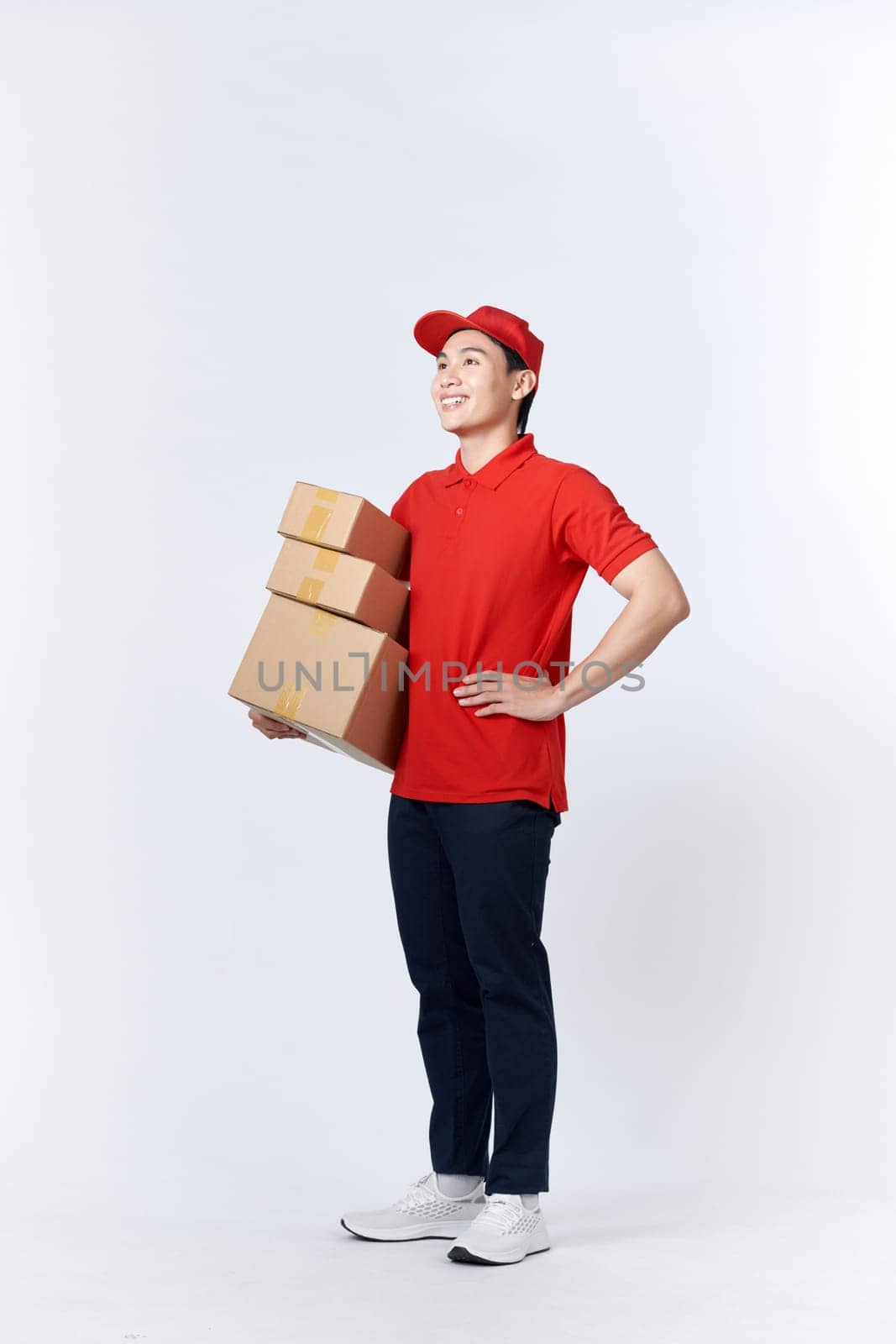 Young asian man holding delivery package smiling happy and positive by makidotvn