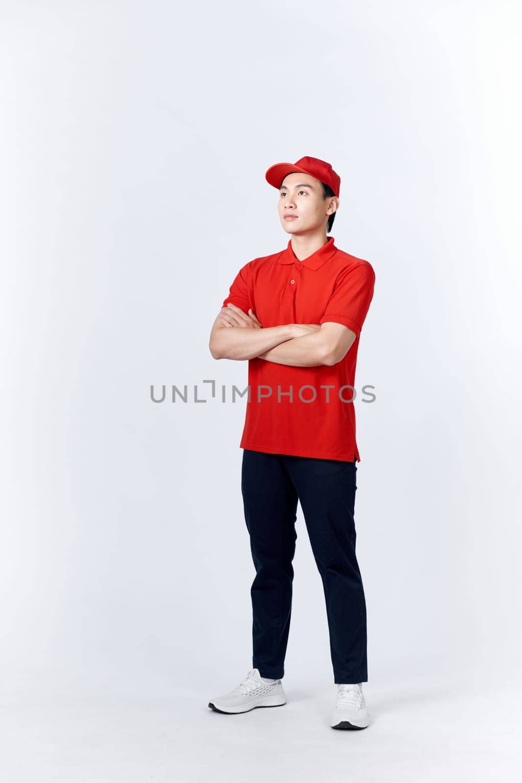 Young asian man in uniform red and cap standing arms crossed with confident isolated on white background by makidotvn