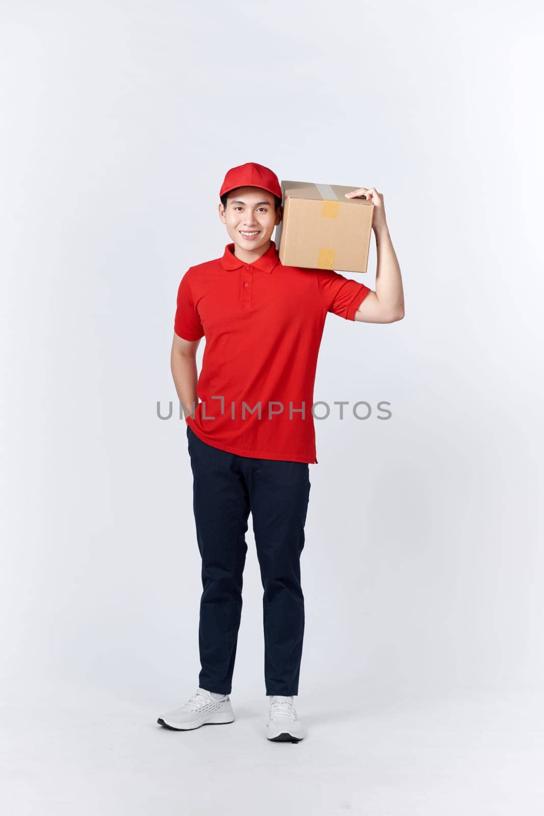 Asian delivery man or passenger holding a cardboard box ready to delivery isolated with clipping path and copy space on white background. by makidotvn
