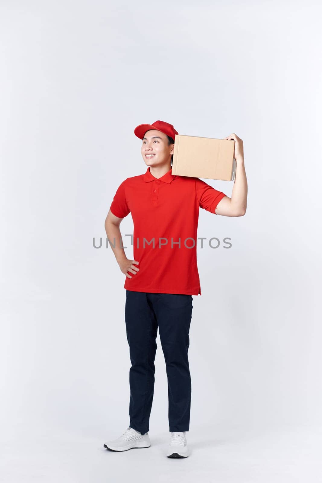Young man holding delivery package looking positive and happy standing and smiling  by makidotvn