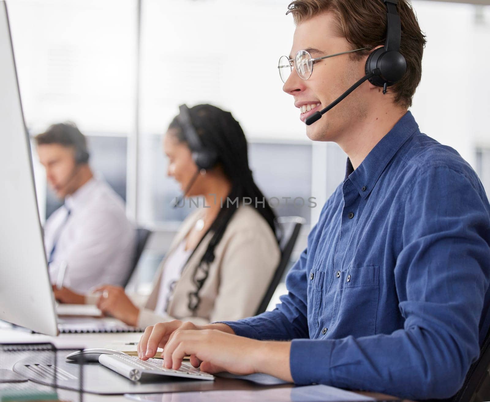 Man, call center and typing on computer, smile in office and working on customer service in workplace. Telemarketing, desktop and happiness of person, male sales agent or consultant consulting online.