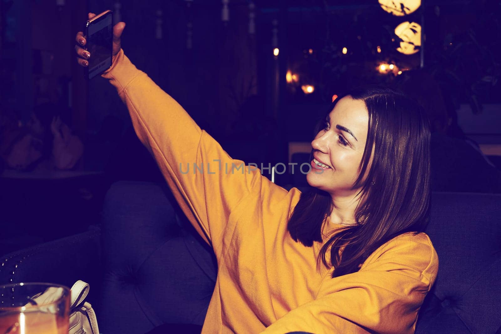 Nice cheerful smiling young woman taking a selfie in a cafe, pub by jovani68