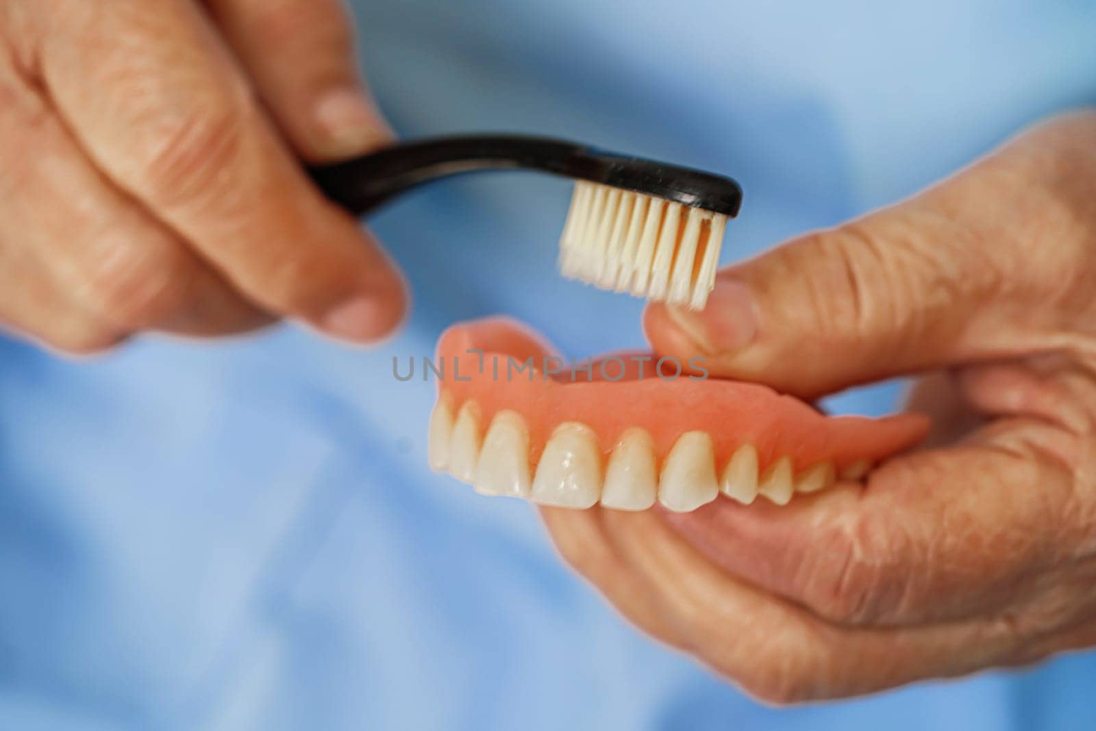 Asian senior woman patient brush teeth denture with toothbrush for chew food.