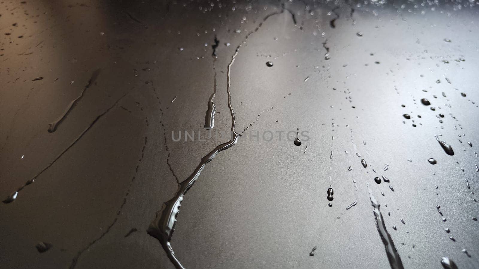 Water drops on black plastic. Surface with wet background. Abstract texture and pattern full of water. Raindrops of rain for overlaying on window with partial focus. Concept of autumn weather