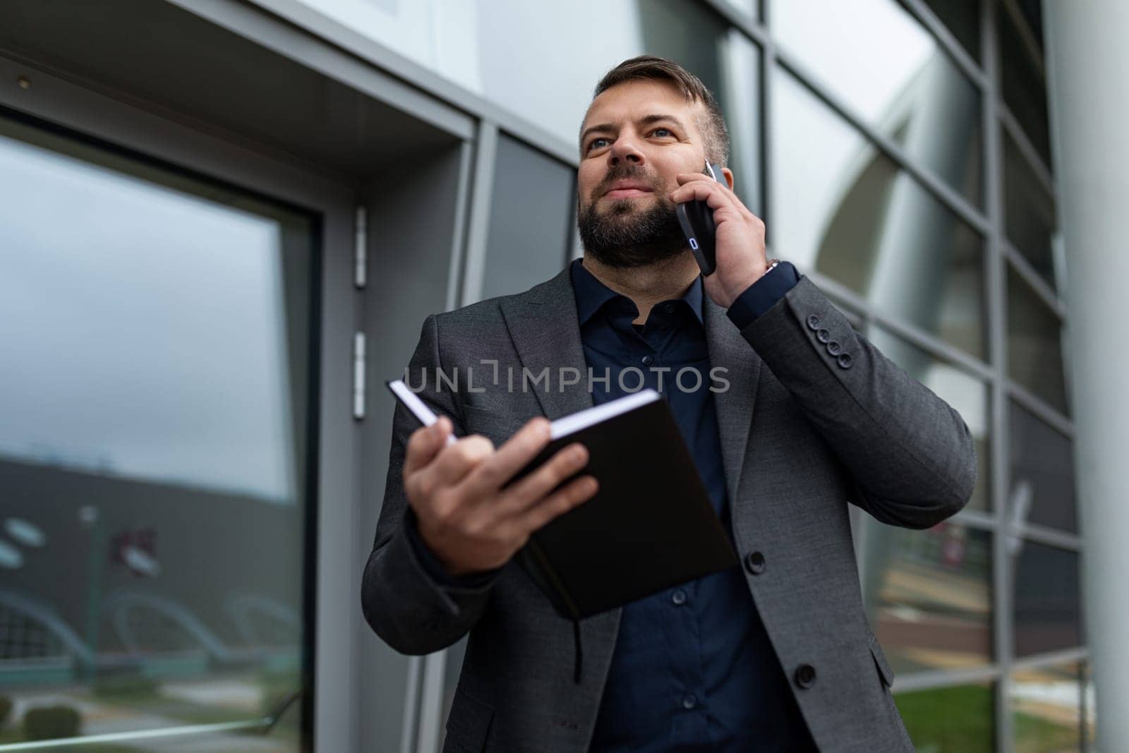 presentable business man talking on the phone with a diary in his hands.
